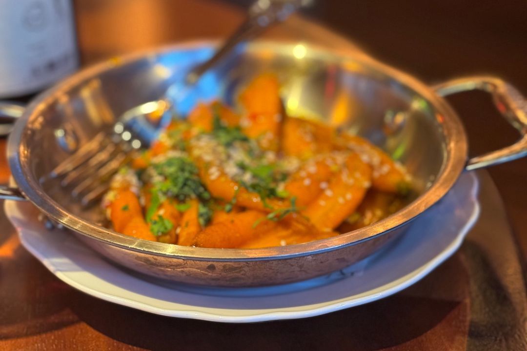 Roasted carrots with herbs and sesame seeds in a metal pan.